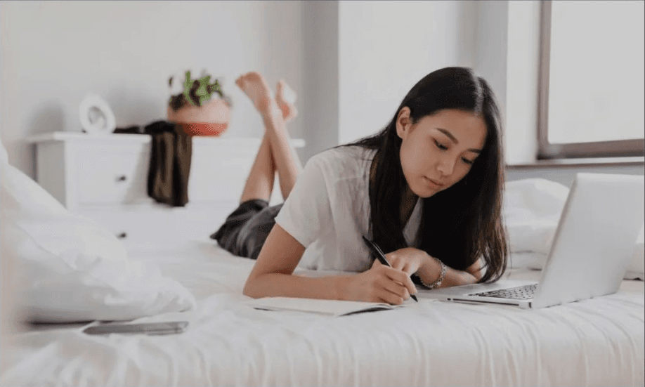 A bright home moment with focused writing on the bed, conveying an undisturbed daily rhythm