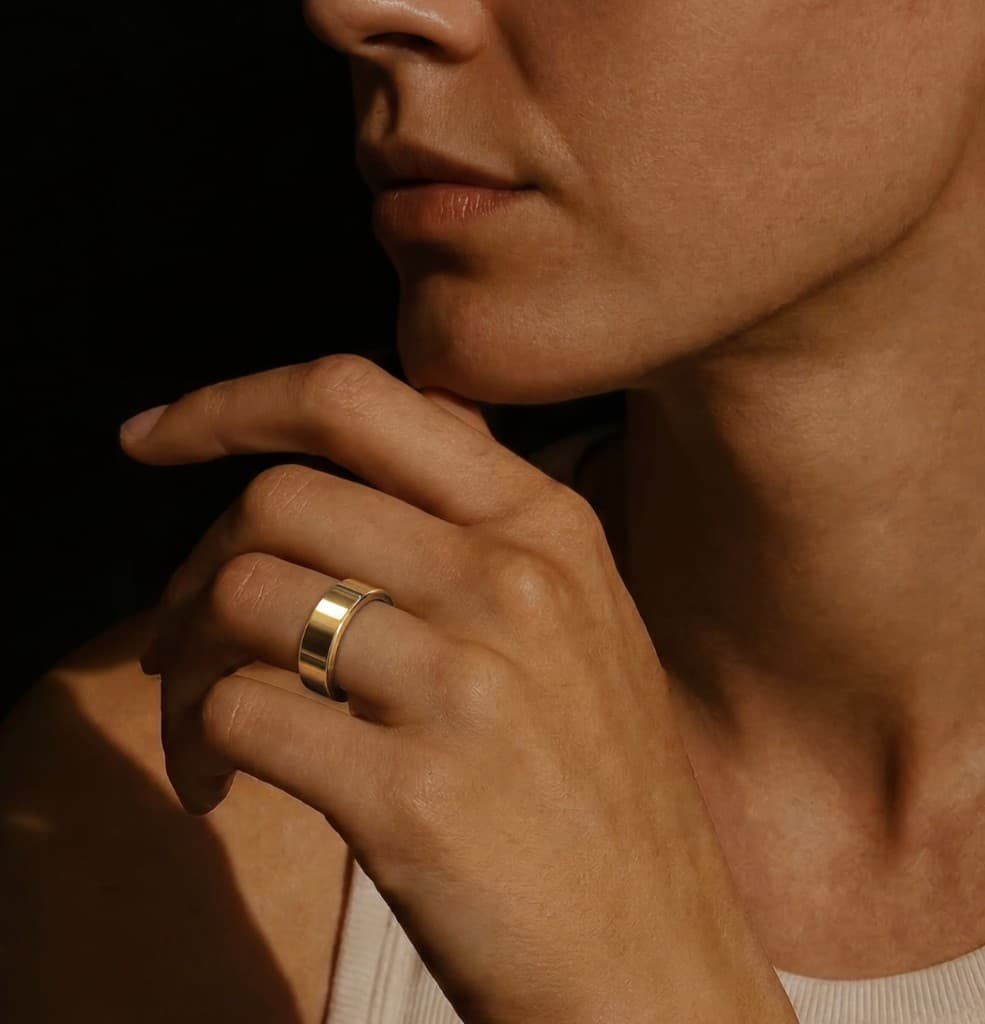 Close-up of a gold smart ring on a finger, conveying lightweight fit and premium texture